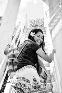 Portrait of smiling young woman walking on staircase