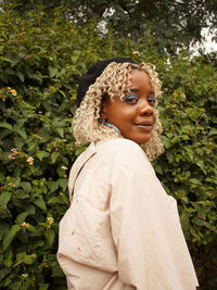 Portrait of young woman standing against plants