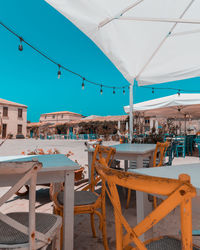 Chairs and tables at swimming pool against buildings