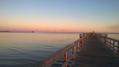 Pier over sea against sky during sunset