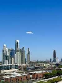 Buildings in city against clear blue sky