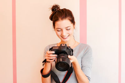 Portrait of smiling young woman holding camera