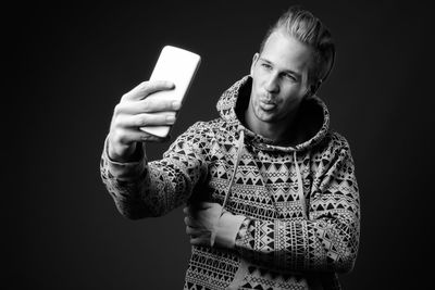 Young man using mobile phone against black background