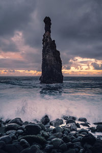 Rocks on beach against sky during sunset