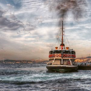 Boats in sea against cloudy sky