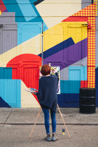 Rear view of woman standing against multi colored building