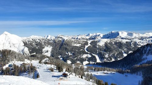 Scenic view of snow covered mountains against blue sky