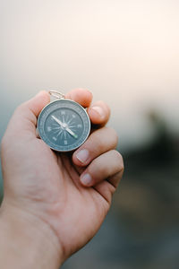 Close-up of hand holding clock against blurred background