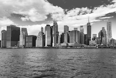 Sea by modern buildings against sky in city