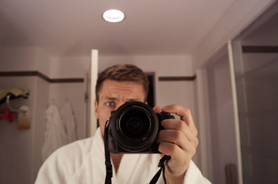 Man photographing with digital camera in bathroom