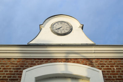 Low angle view of clock on wall against building