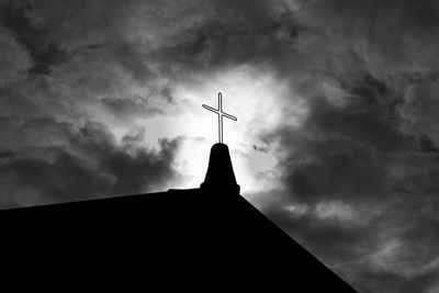 Low section of silhouette church against cloudy sky