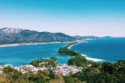 High angle view of sea and mountains against clear blue sky