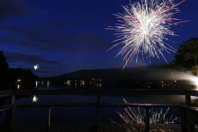 Firework display over river against sky at night