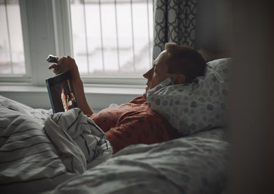 Rear view of woman lying on bed at home