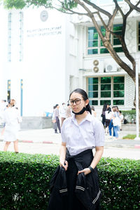 Portrait of young woman standing against trees