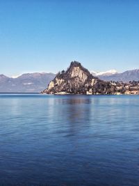 Scenic view of sea and mountains against clear blue sky