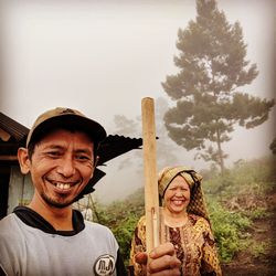 Portrait of smiling young woman standing against trees