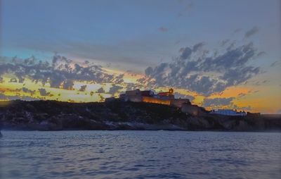 Scenic view of sea and buildings against sky at sunset