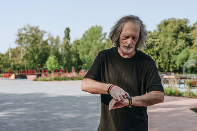 Senior man checking pulse rate on smart watch in park