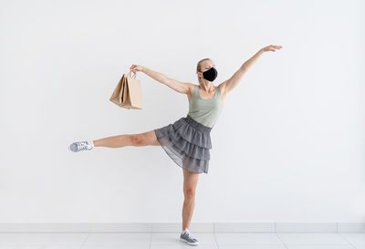 Young woman with arms raised standing against white background