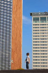 Full length side view of woman standing against building