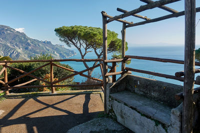 Metallic railing by sea against sky