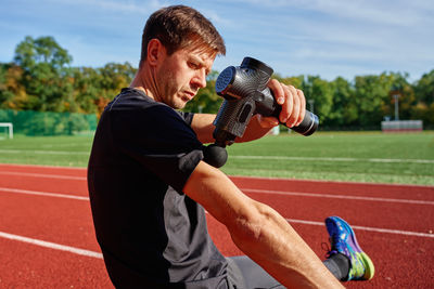 Side view of young man lifting dumbbell at park