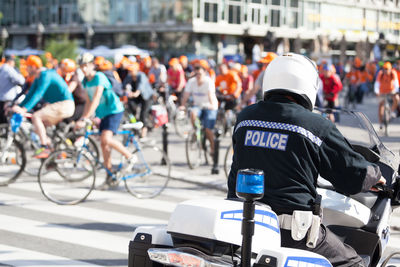 Rear view of police man sitting on motorcycle during sports race in city