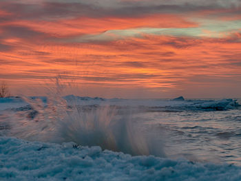 Winter landscape from the sea shore, blurred wave slags against frozen ice cubes, blurred sunset 