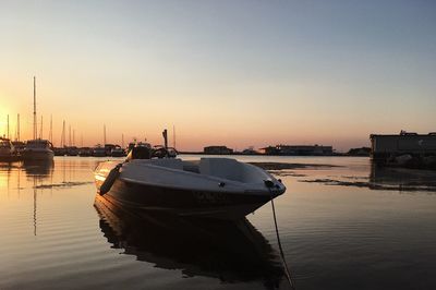 Boats moored in marina at sunset