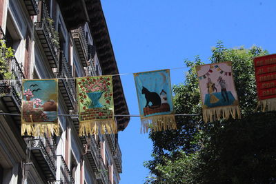 Low angle view of flags hanging amidst buildings against sky