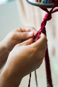 Close-up of hand weaving macramé hanging planter.