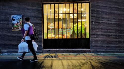 Man walking by building in city at night