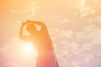 Rear view of woman photographing against sky during sunset