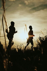 Silhouette man standing on field against sky during sunset