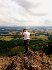 Rear view of man standing on landscape against sky