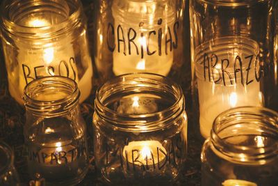 Close-up of illuminated tea light candles in glass jars with text