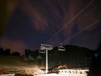 Low angle view of ski lift over landscape against sky