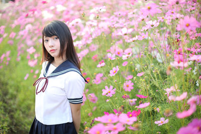 Portrait of woman standing by pink flowering plants