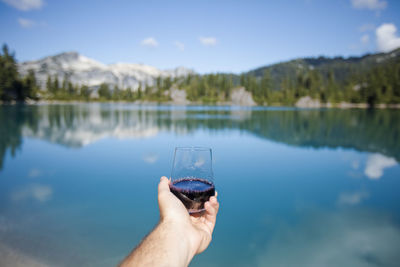 Man hand on lake against sky