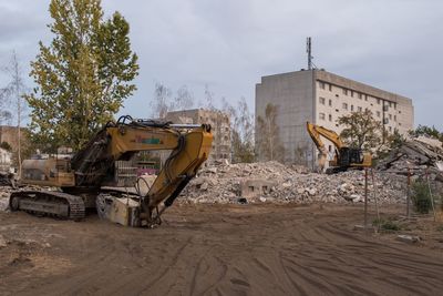 Construction site by road against sky in city