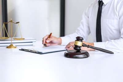 Midsection of judge writing on book at table