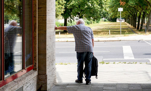 Rear view of man standing on footpath