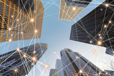 Low angle view of buildings with connecting dots against sky during sunset