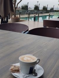 Coffee cup on table by swimming pool