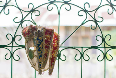 Close-up of mask hanging on metallic fence