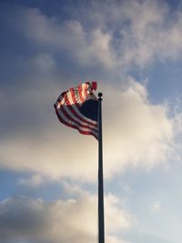 Low angle view of american flag waving against sky