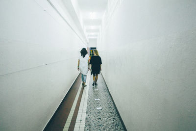 Rear view of friends walking in corridor