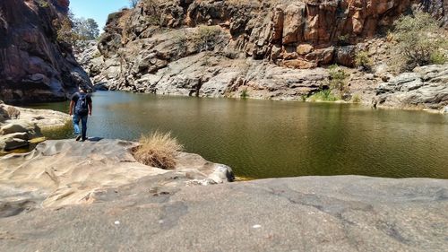 Rear view of man standing on rock against sky